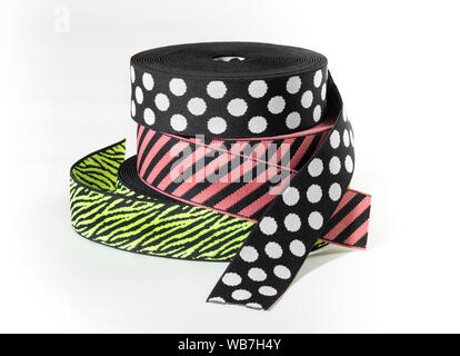 Colorful elastic ribbons or bands in rolls with stripes and polka dot patterns stacked together on white for use as supplies in the fashion industry Stock Photo