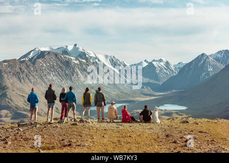 Group of friends or tourists stands on view point in mountains area and having rest Stock Photo