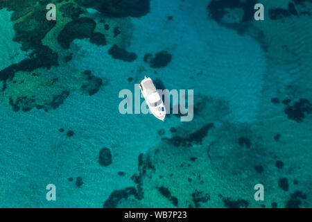 View from above, stunning aerial view of a luxury yacht floating on an emerald green bay of water in Sardinia. Maddalena Archipelago National Park Stock Photo