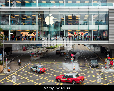 Red taxi cabs passing by the Apple Store in Central. Hong Kong, China. Stock Photo