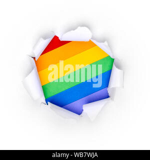 Paper hole in white paper with ragged edges with LGBT rainbow colors background. Stock Photo