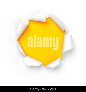 Paper hole in white paper with ragged edges with yellow background. Stock Photo