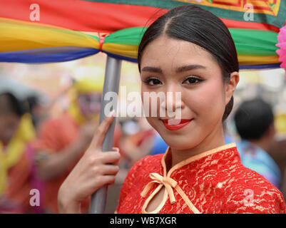 Costumed female participant and flag carrier at Bangkok's traditional Chinese New Year street parade poses for the camera. Stock Photo