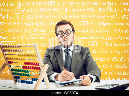 Nerd accountant does calculation of company revenue on yellow background Stock Photo