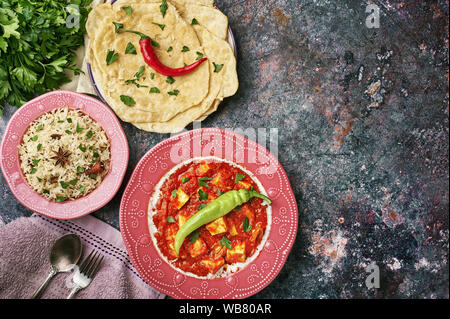 Paneer Makhani, Jeera Rice and paratha in pink plate on dark background. Paneer Makhani is an indian cuisine curry with paneer cheese, tomatoes and sp Stock Photo