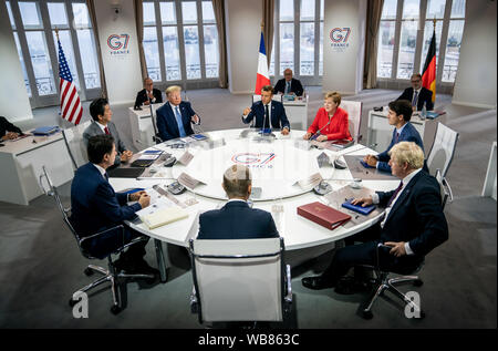 Biarritz, France. 24th August, 2019. France's President Emanuel Macron (M back), speaking at the first working session of the G7 summit, alongside (r clockwise) Chancellor Angela Merkel (CDU), Canada's Prime Minister Justin Trudeau, British Prime Minister Boris Johnson, EU Council President Donald Tusk, Acting Prime Minister Italy Giuseppe Conte, Japan's Prime Minister Shinzo Abe and US President Donald Trump. The G7 summit will take place from 24 to 26 August in Biarritz. Photo: Michael Kappeler/dpa/Alamy live news Stock Photo