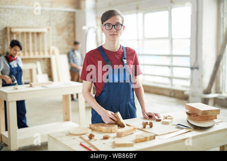 Waist up portrait of young carpenter looking at camera while working with wood in workshop Stock Photo