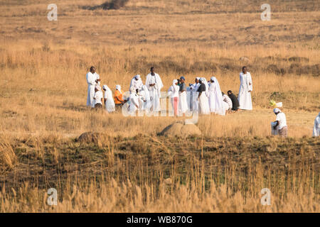 African black people dressed in white apparel or clothing holding a religious outdoor ceremony or meeting at sunset in Winter Johannesburg, Gauteng Stock Photo