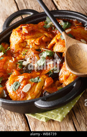 Homemade chicken thighs stewed with eggplant in tomato sauce close-up in a pan on the table. vertical Stock Photo
