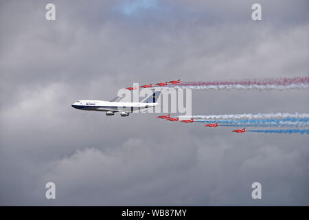 The British  Red Arrows aerobatic display team celebrate British Airways 100th birthday with a flypast in formation with a BOAC Boeing 747 airliner Stock Photo