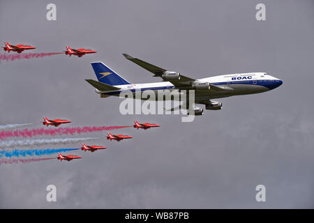 The British  Red Arrows aerobatic display team celebrate British Airways 100th birthday with a flypast in formation with a BOAC Boeing 747 airliner Stock Photo