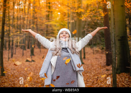 Girl walking in the park in autumn and smiles with open arms Stock Photo