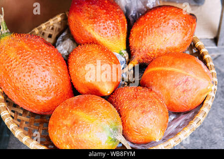 Gac perennial melon fruit as Exotic asian food in Hanoi in Vietnam. Street market with Vietnamese cousine. Local produce from garden. Healthy vegetari Stock Photo