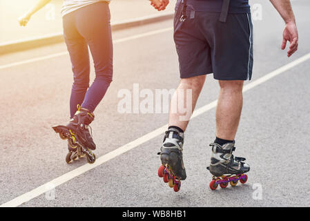 happy couple riding on roller skates holding hands in city Stock Photo