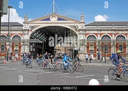 Cyclists cycling group riding bikes in the street outside the front of Smithfield Market building in the City of London EC1 England UK   KATHY DEWITT Stock Photo