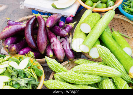 Asian vegetable assortment such as green bitter gourd and egg-plant on display in Hoi An in Vietnam in Asia. Variety of local stuff on Vietnamese stre Stock Photo