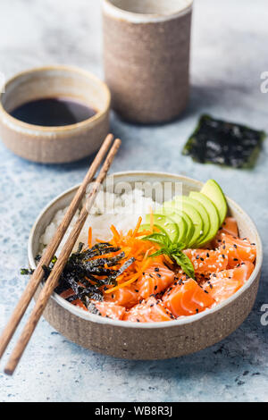 Hawaiian salmon poke bowl with seaweed, avocado, carrot, sesame seeds and rice. Stock Photo