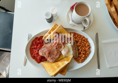plate of English breakfast with mug of tea on a cafe table Stock Photo