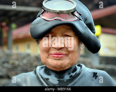 Professional free-diving South Korean woman (haenyeo) wears a wet diving suit and poses with her diving mask and diving hood. Stock Photo