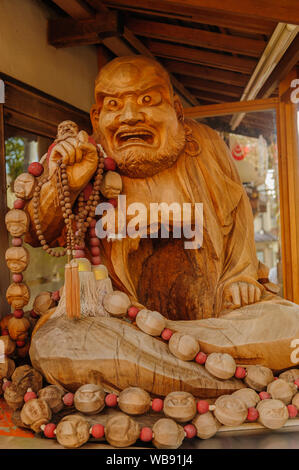 Carved wooden statue of an angry looking monk with a prayer beads in his hand reveals rich details of traditional artwork, Kyoto Japan November 2018 Stock Photo