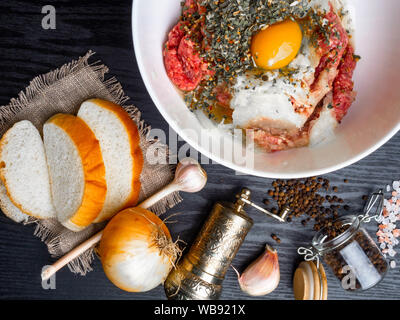 minced meat with fresh onion, garlic, herbs on wooden background Stock Photo