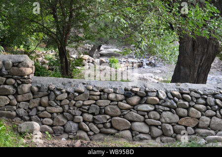 Stone wall in an orchard near the village of Sentyab in the Nuratau mountains, central Uzbekistan Stock Photo