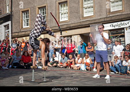 Edinburgh Fringe crowds, Grassmarket and Royal Mile, Scotland, UK. 25th August 2019. Crowds were out for the very sunny last Sunday of The 2019 Edinburgh Festival Fringe keeping a constant queue in the Grassmarket at the converted Police Box for ice cream and the restaurants were full to capacity. Shannen No Bones Jones drew a crowd at foot of Victoria Street for her archery contortionist act and the Royal Mile was very busy. Stock Photo