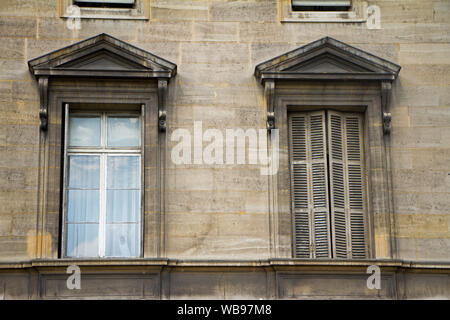 Close up of traditional windows with porticoes and shutters on the facade of a building in the historical center of Paris Stock Photo