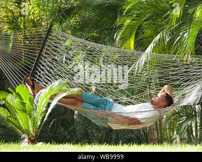 A man in a hotel lying in a hammock. Stock Photo