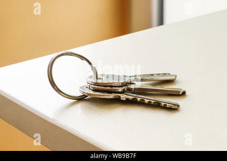 Set of three house keys on the ring on table in a room. Bunch of apartment keys close-up. To forget keys at home consept. Close-up. Stock Photo