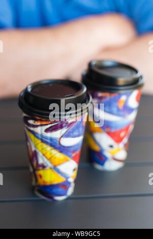 Vertical selective closeup shot of two colorful takeaway cups Stock Photo