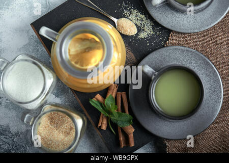 Transparent glass teapot with chitrus tea and cups, tea set on a wooden table. Close up, gray background, soft light Stock Photo