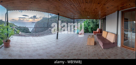 Sunset in the distance over the ocean with mountains and dinner tables and trees Stock Photo