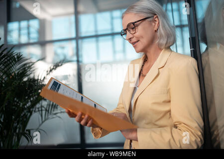 Concentrated Caucasian businesswoman in her 50s reading documents Stock Photo