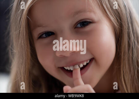 Blue-eyed blond girl laughs and shows the first tooth. children's teeth, loss Stock Photo