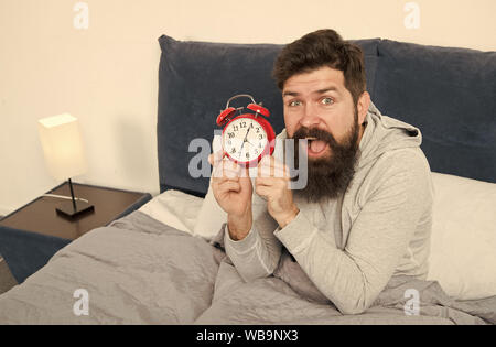 Man bearded hipster sleepy face waking up. Daily schedule for healthy lifestyle. Again unhappy in morning. Alarm clock ringing. Problem early morning awakening. Get up early. Tips for waking up early. Stock Photo