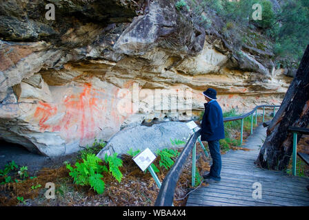 Visitor on boardwalk looking at Aboriginal rock paintings in the Tombs, a sacred area used as a burial site by the Aboriginal inhabitants of the regio Stock Photo