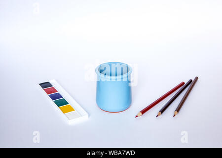 Blue vase for pencils on the white background with various pencils and paints Stock Photo