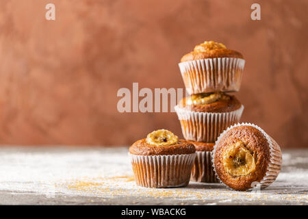 Homemade banana muffins in a stack on a brown background. Healthy vegan dessert. Close-up selective focus. Horizontal frame. Copy space Stock Photo