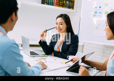 Asian mature business woman smiling and looking at camera while sitting in meeting. Smart middle age lady having discussion. Stock Photo