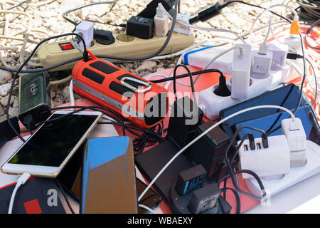 Many electrical plugs connected to a power strip or extension block. Wall chargers plugged in gang socket. Charging gadgets, smartphones and electroni Stock Photo