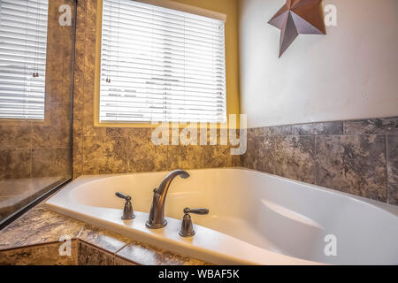Close up of the clean white built in bathtun of a bathroom with marble tile wall Stock Photo