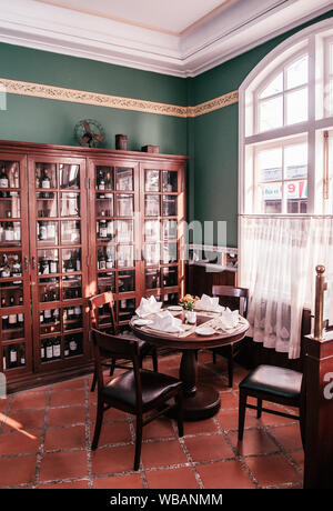 FEB 26, 2014 Dalat, Vietnam - Vintage classic colonial restaurant dining room with wooden wine cabinet. Furnished with old wooden furnitures. Stock Photo
