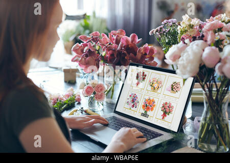 Over shoulder view of busy flower shop owner standing at counter Stock Photo