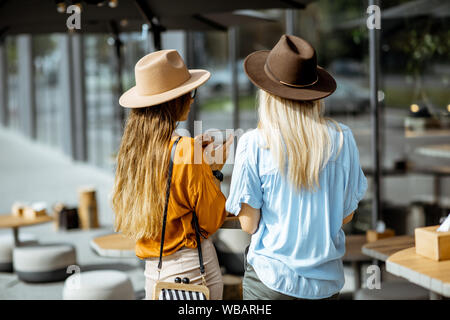 Two girlfriends standing together at the cafe terrace, rear view Stock Photo