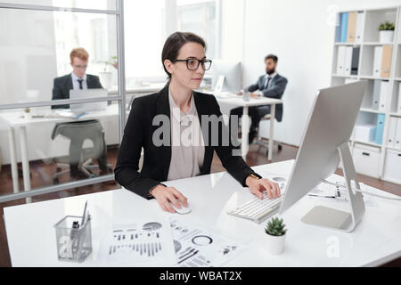 Portrait of young businesswoman wearing glasses using PC Stock Photo