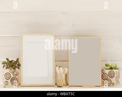 Mock up wooden frames, colorful pencils, houseplants on a white shelf or table on a wooden background Stock Photo