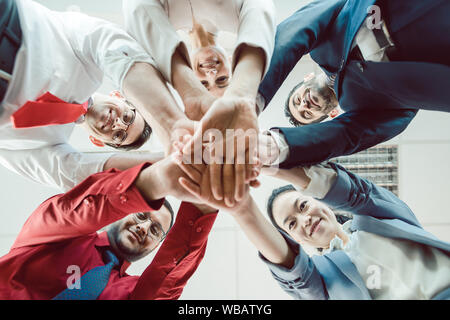 Team of diverse business people stacking their hands together Stock Photo