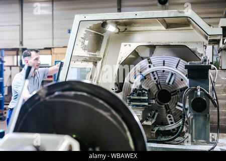 Worker operating a CNC lathe in factory Stock Photo