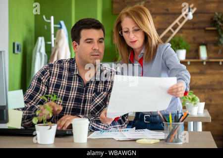 Man and female office workers looking at documents in start up company office Stock Photo
